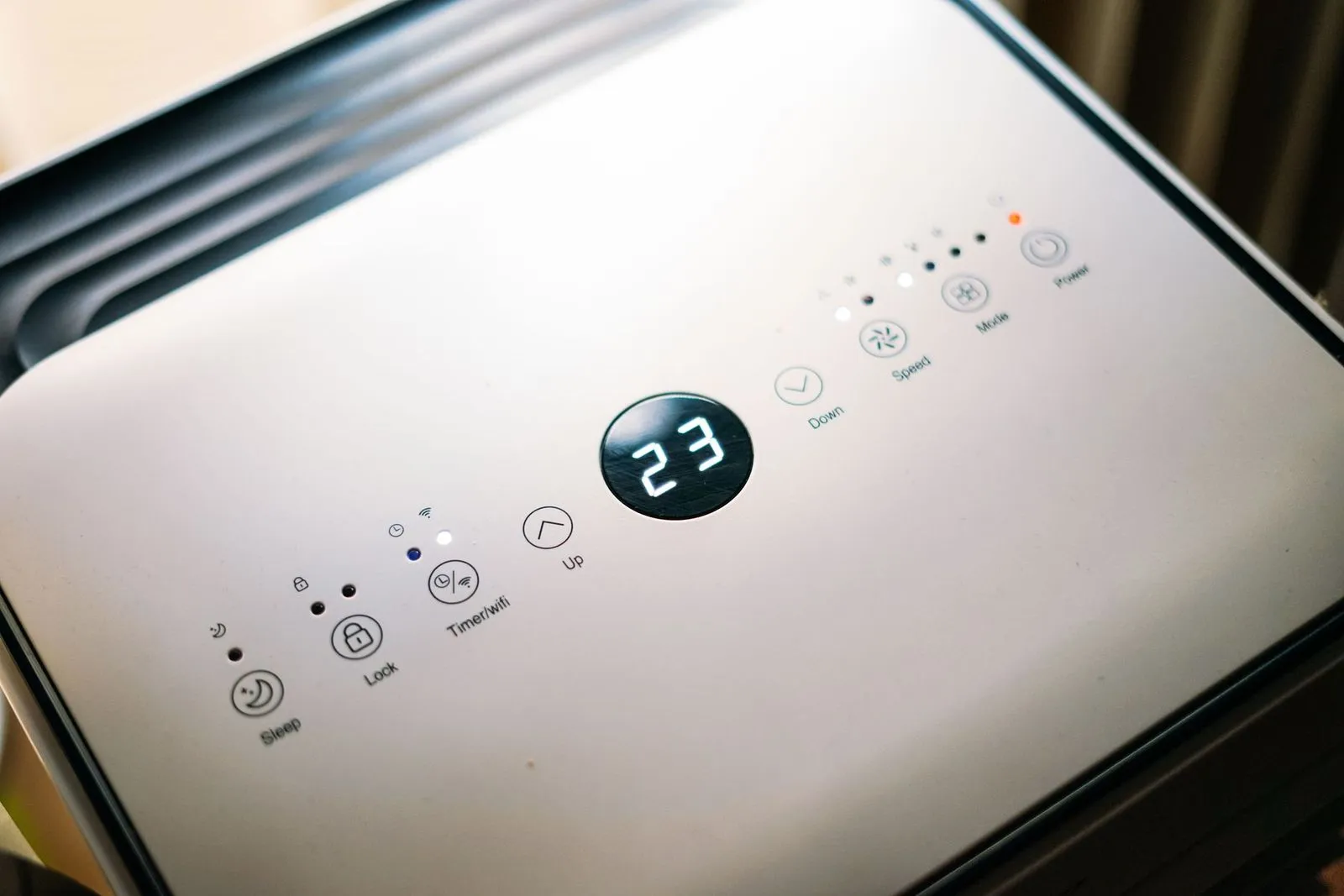 Painel de controle branco com visor digital marcando 23, com botões de sono, timer e velocidade.